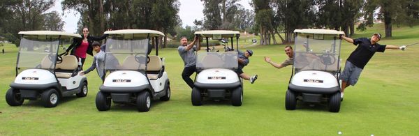 golfers posing for a photo, hanging out golf carts
